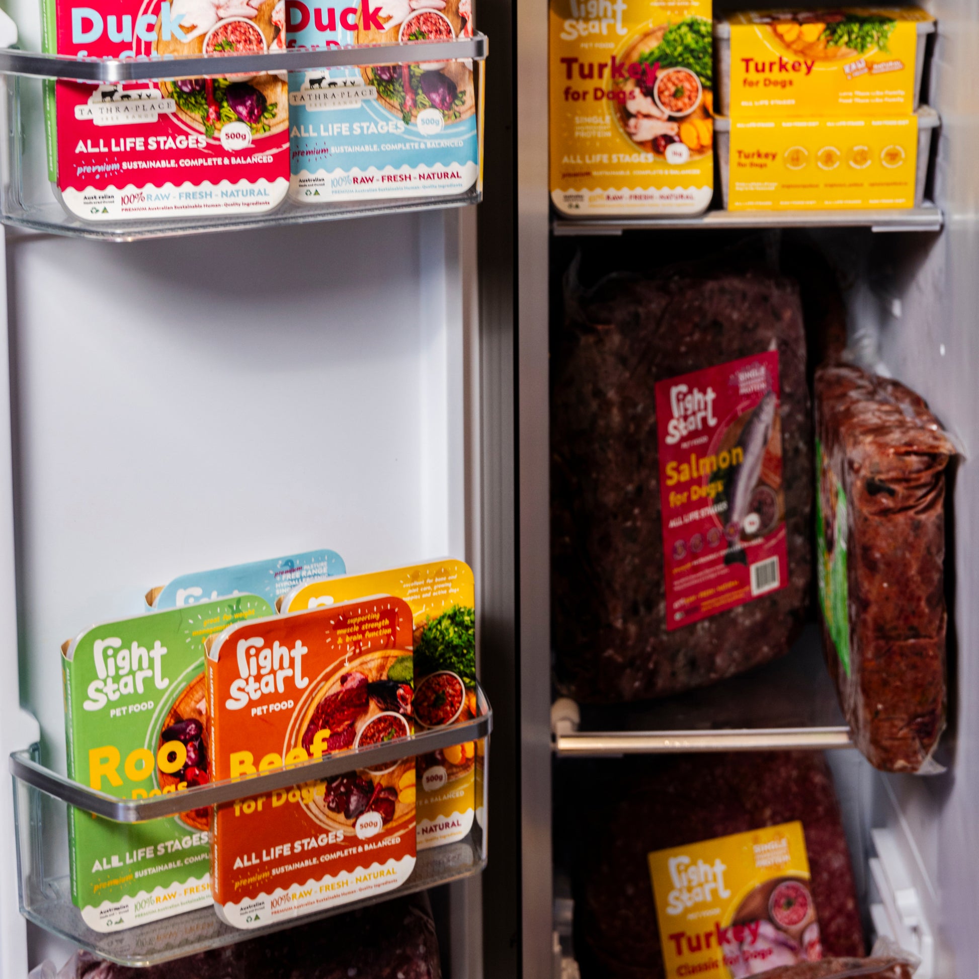 hand reaching for frozen dog food in fridge. yellow, pink, blue, green fun packaging filling the fridge labelled with proteins and right start pet food  